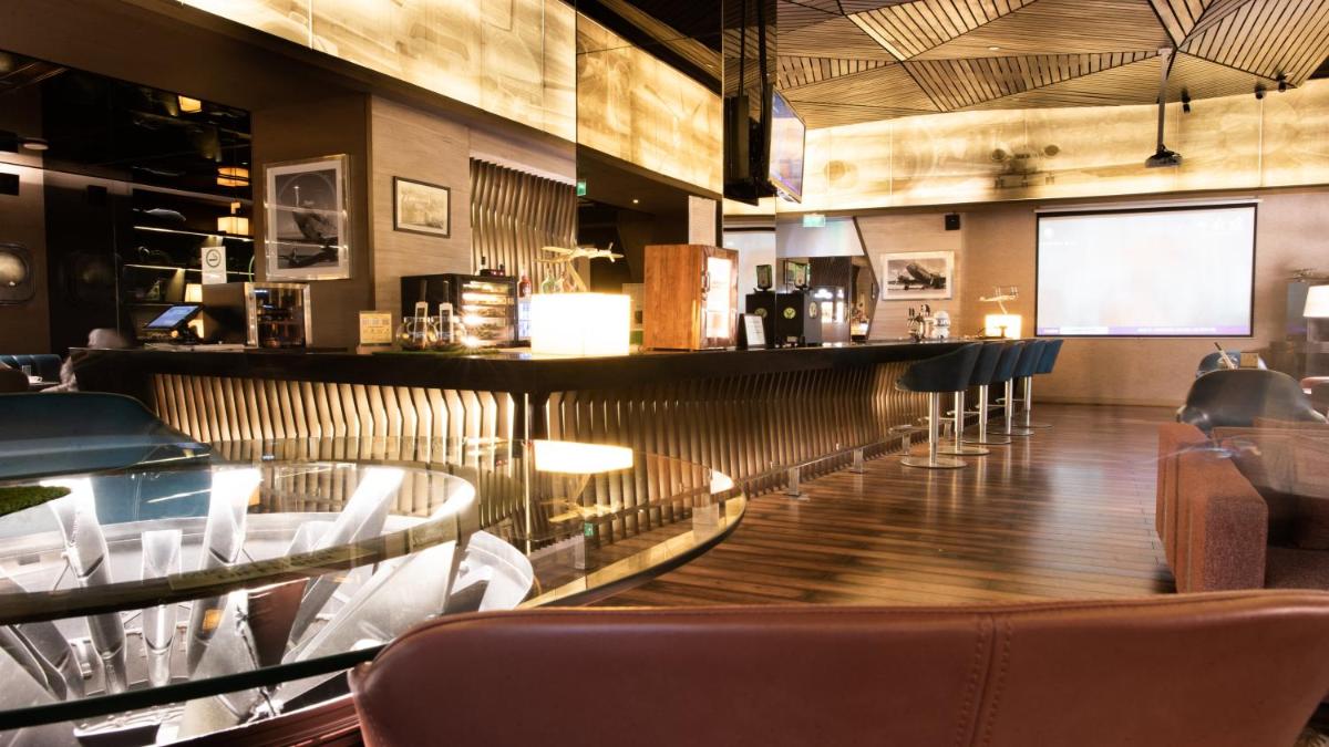 a restaurant with a bar with white chairs at Holiday Inn New Delhi Aerocity by IHG in New Delhi