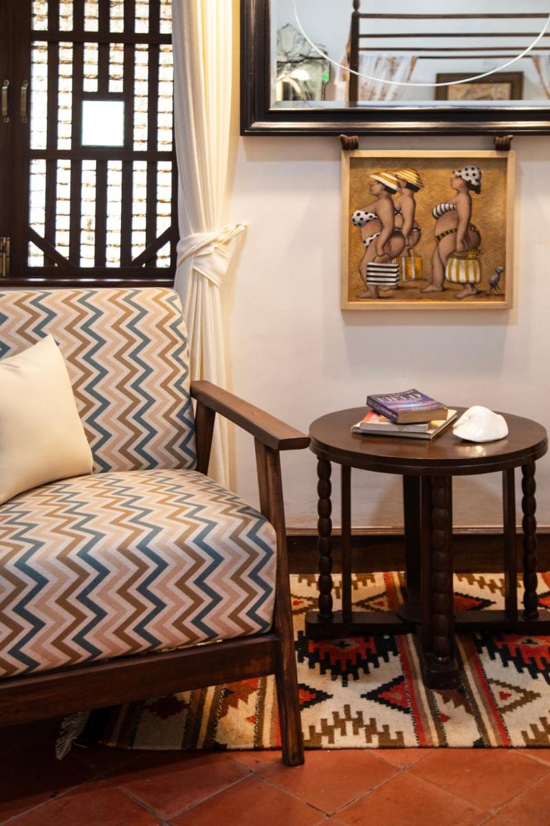 a living room with a chair and a table at Lamrin Ucassaim Goa An Indo Portuguese Hotel in Moira