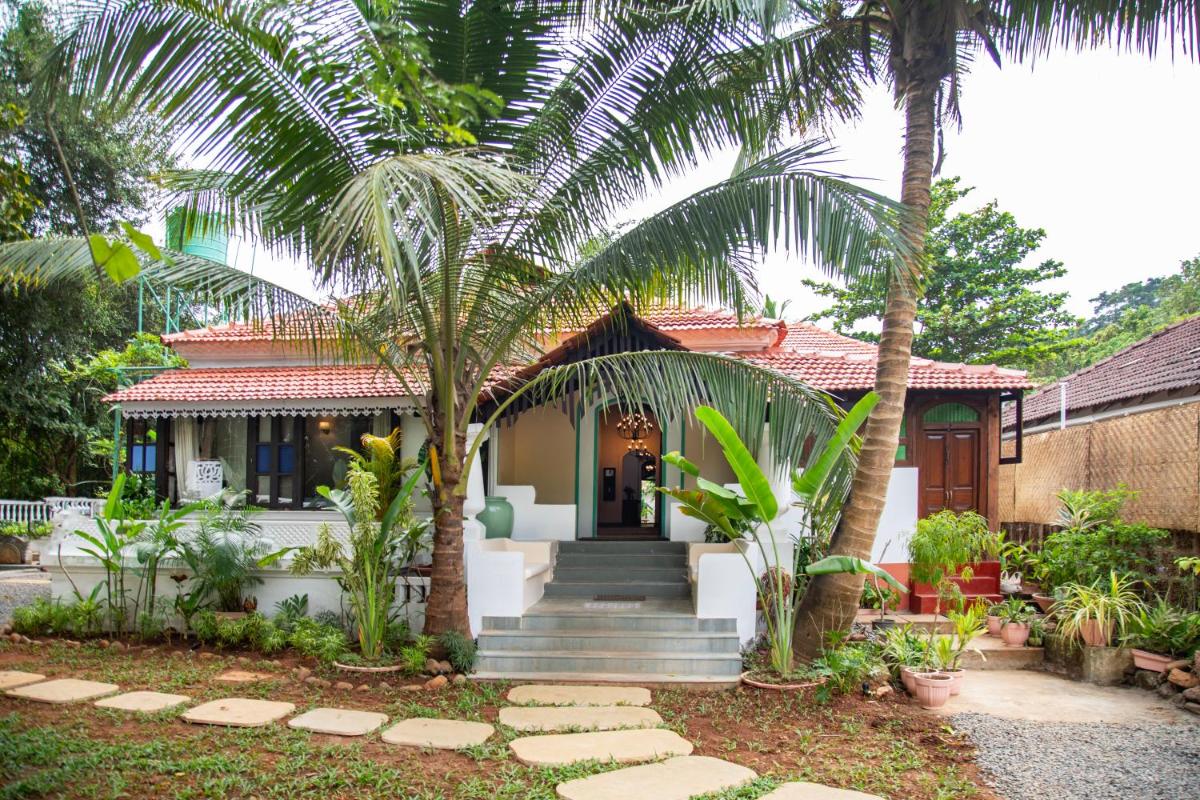 a house with palm trees in front of it at Lamrin Ucassaim Goa An Indo Portuguese Hotel in Moira