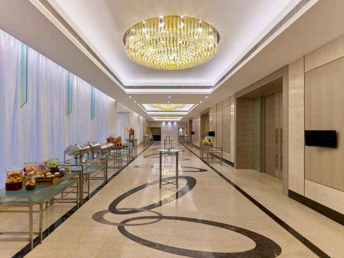 a lobby with a chandelier and a long corridor at Crowne Plaza Ahmedabad City Centre by IHG in Ahmedabad