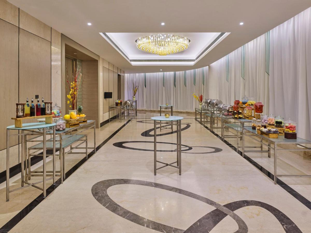a hotel lobby with tables and a chandelier at Crowne Plaza Ahmedabad City Centre by IHG in Ahmedabad
