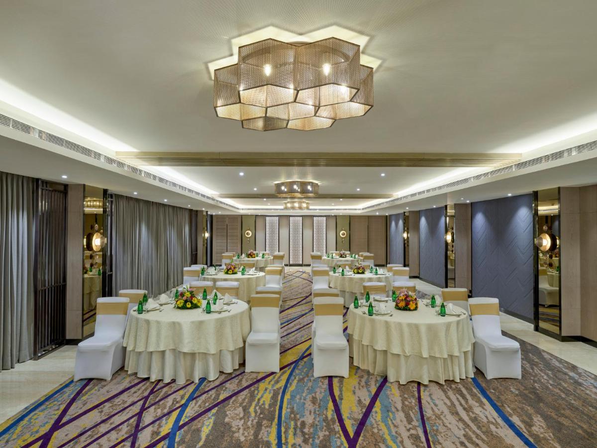 a conference room with white tables and chairs and a chandelier at Crowne Plaza Ahmedabad City Centre by IHG in Ahmedabad