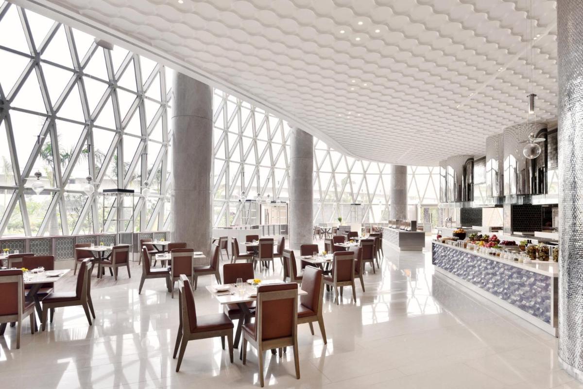 a dining room with tables and chairs and windows at JW Marriott Hotel Kolkata in Kolkata
