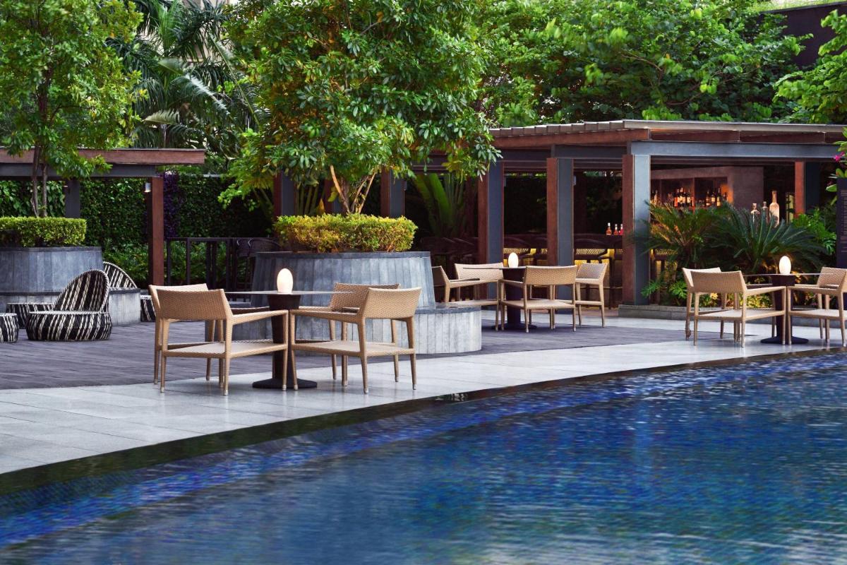 a pool with chairs and a table next to a building at JW Marriott Hotel Kolkata in Kolkata
