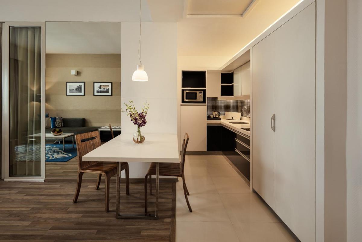 a kitchen and dining room with a white table and chairs at Grand Mercure Bangalore - An Accor Brand in Bengaluru