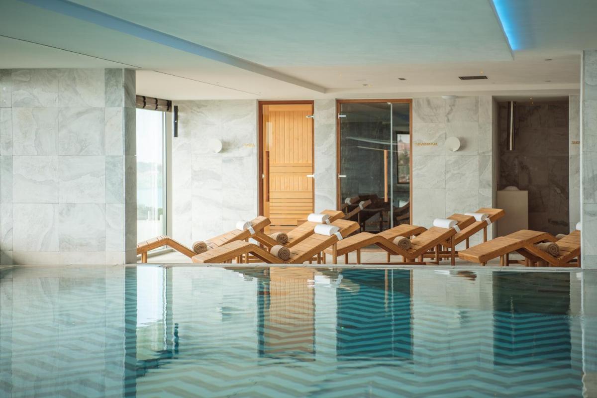 um quarto com uma piscina com cadeiras e mesas em EVOLUTION Cascais-Estoril Hotel em Estoril
