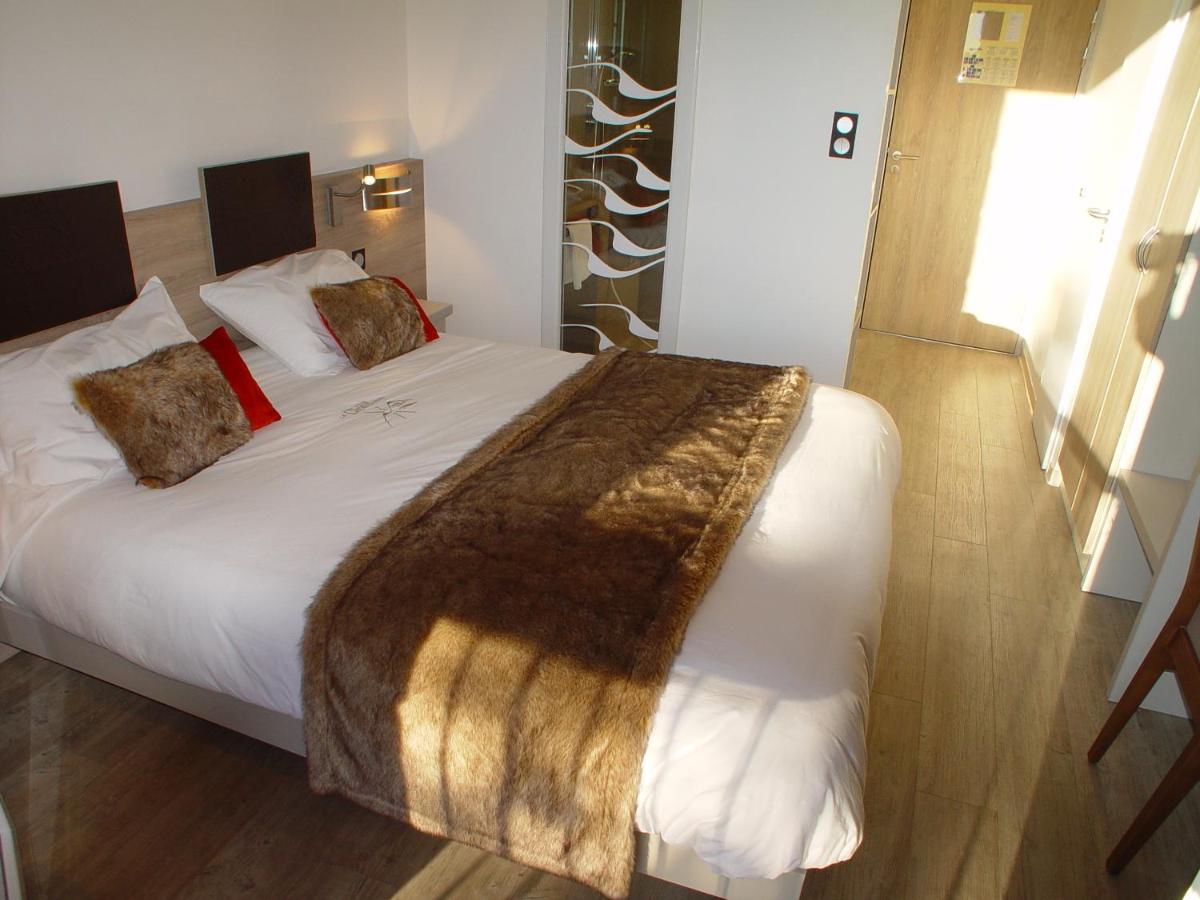 une chambre avec un grand lit blanc avec une couverture marron dans l'établissement Hotel et Résidence Le Clos Cerdan, à Mont-Louis