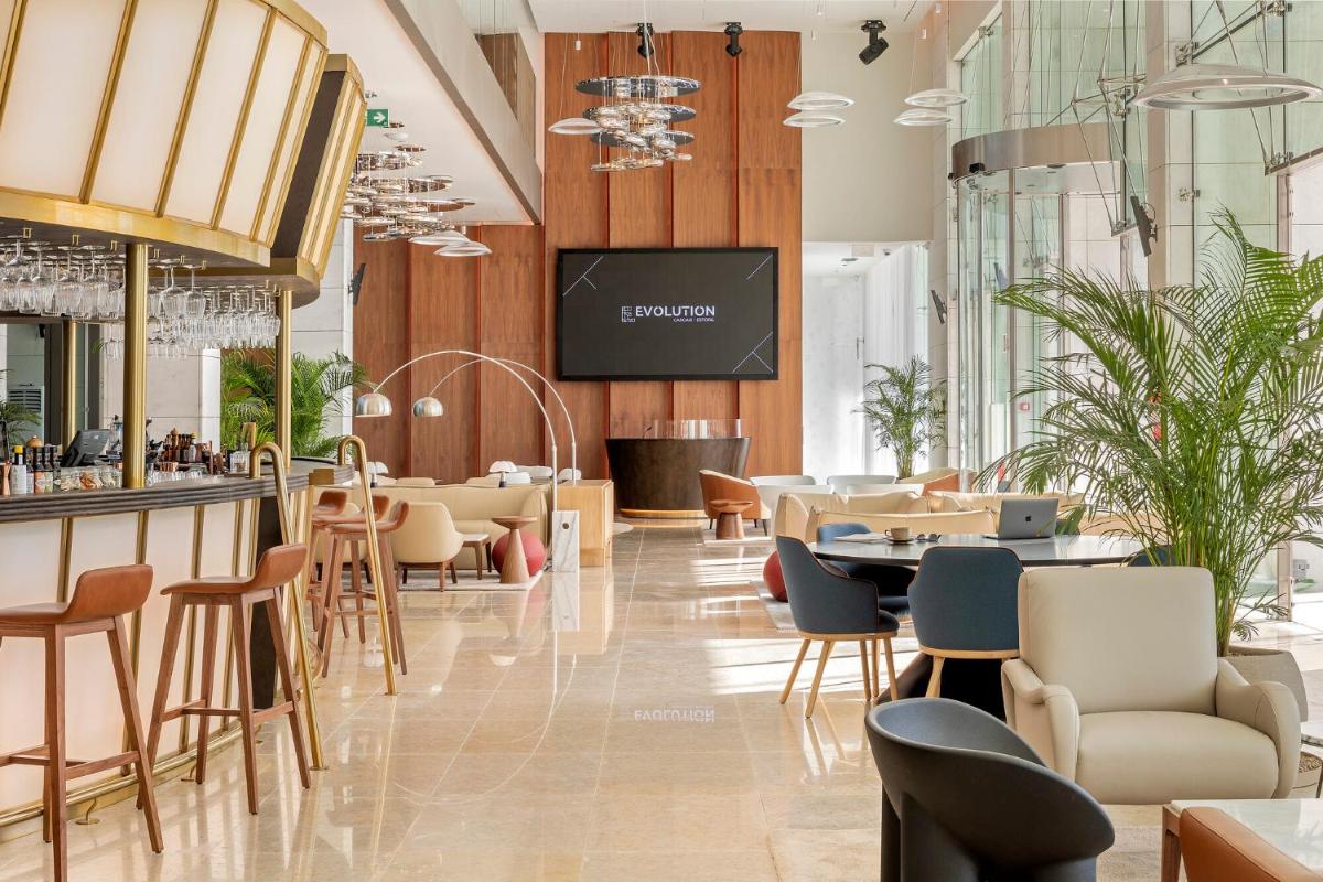 um restaurante com bar, mesas e cadeiras em EVOLUTION Cascais-Estoril Hotel em Estoril