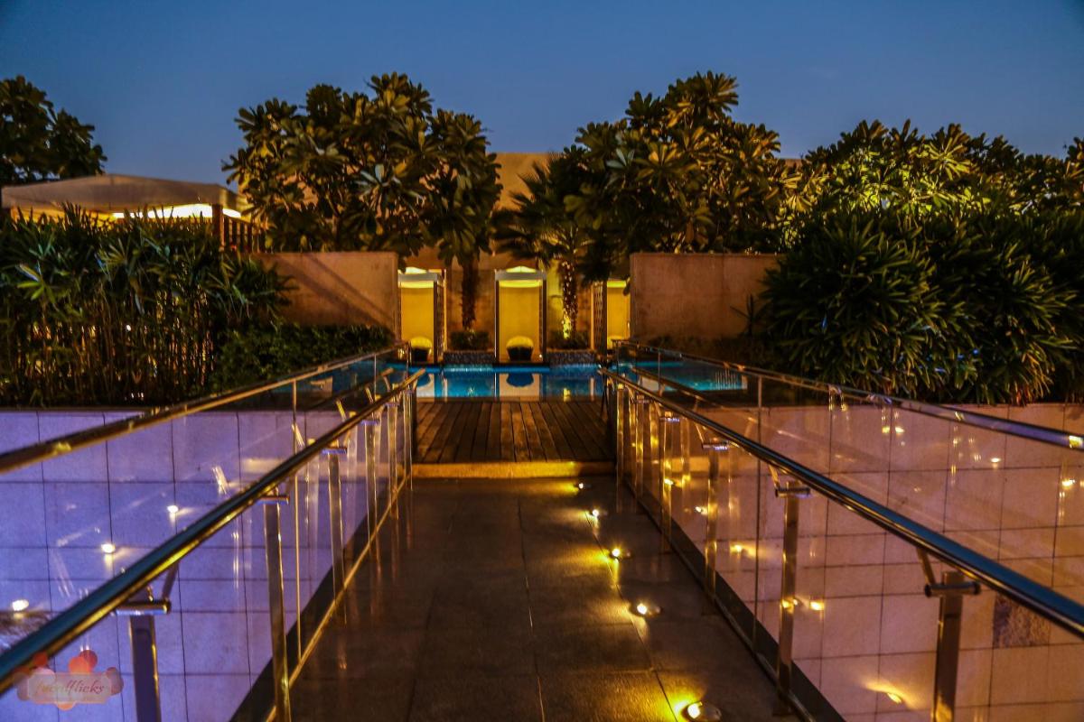 a swimming pool with lights on the side of a building at Taj City Centre Gurugram in Gurgaon