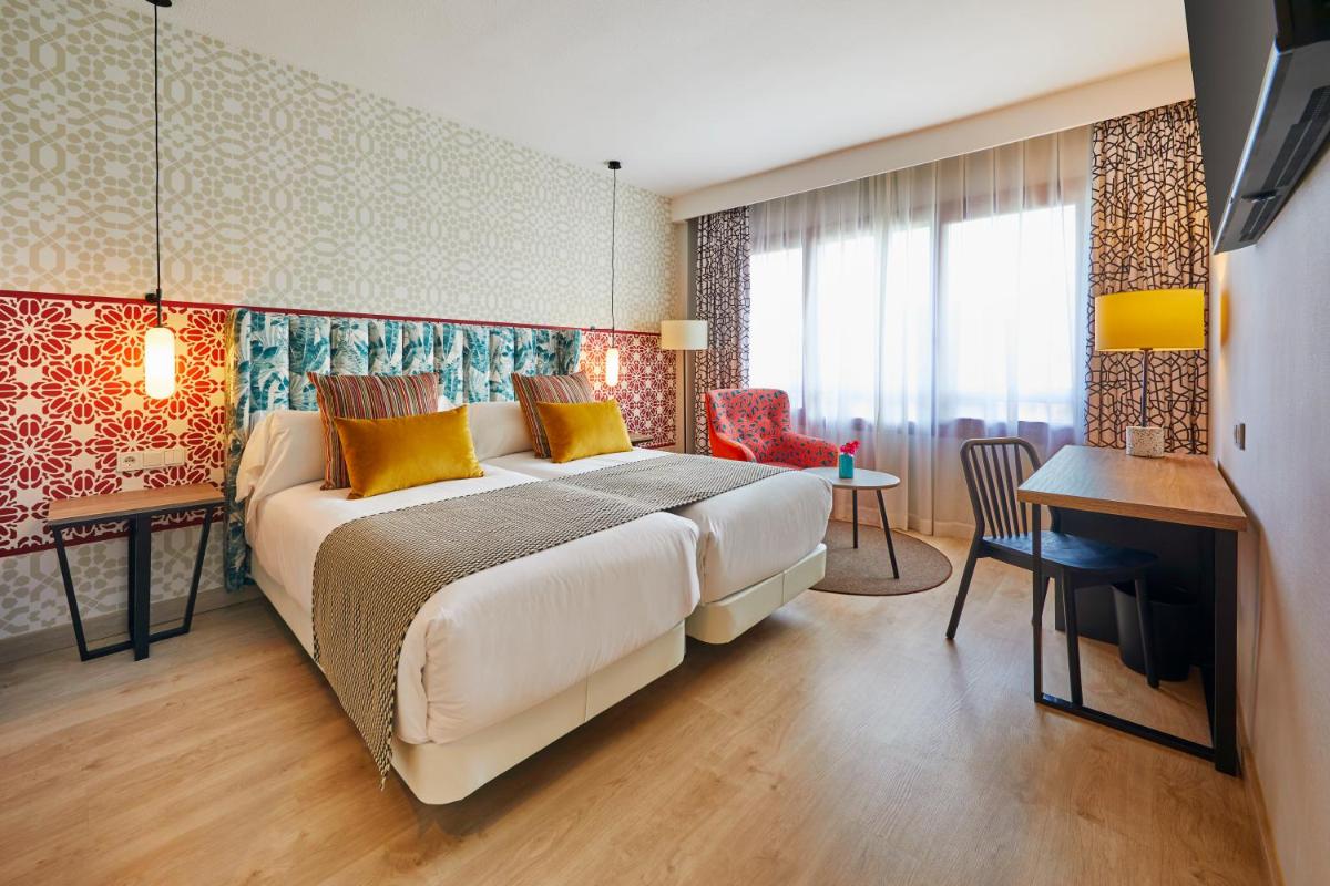 Un dormitorio con una cama grande y una mesa y sillas. en Hesperia Sevilla, en Sevilla