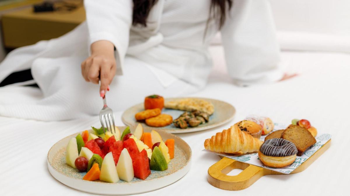 a person eating food on a table with plates of food at Holiday Inn New Delhi Aerocity by IHG in New Delhi