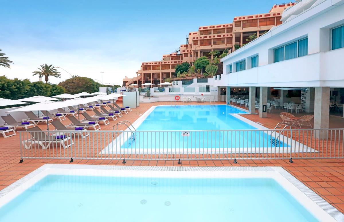 Una piscina con tumbonas y un hotel. en FERGUS Cactus Garden, en Playa de Jandía