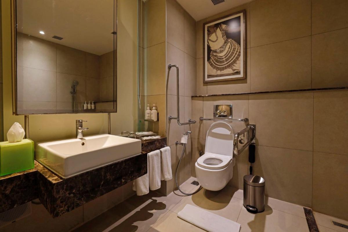 a bathroom with a sink and a toilet and a mirror at Holiday Inn Chennai OMR IT Expressway by IHG in Chennai