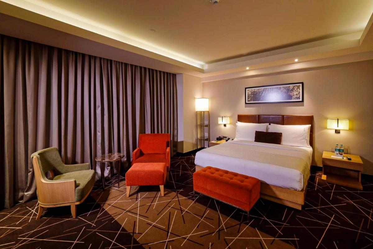 a hotel room with a bed and a chair at Holiday Inn Chennai OMR IT Expressway by IHG in Chennai
