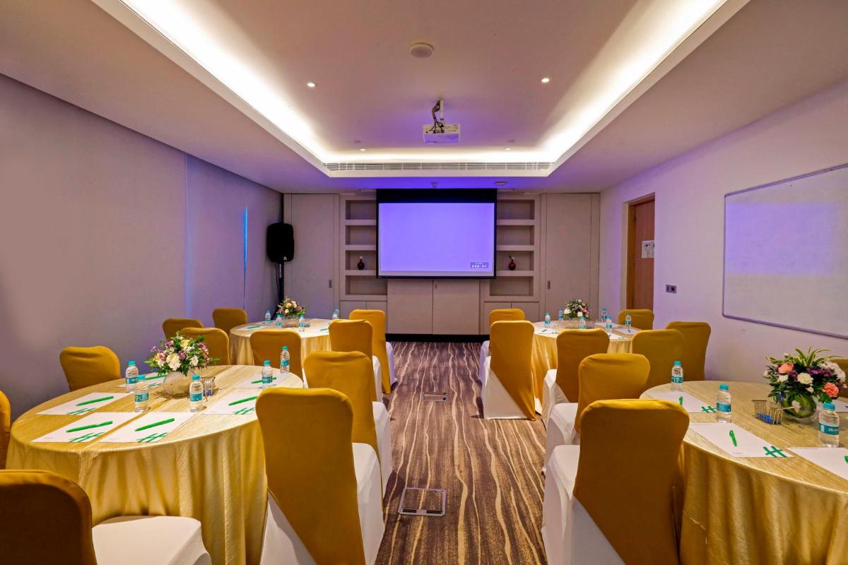 a conference room with tables and chairs and a projection screen at Holiday Inn Chennai OMR IT Expressway by IHG in Chennai