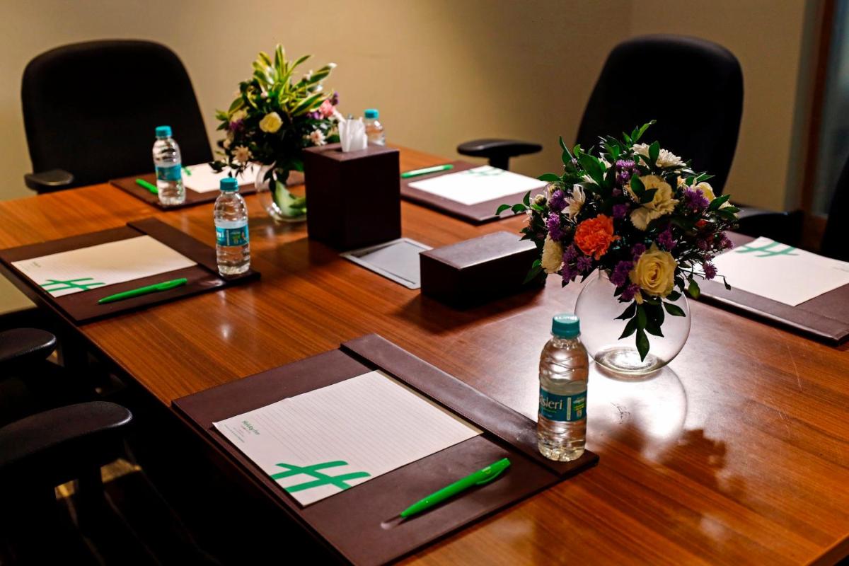 a long wooden table with flowers and bottles of water at Holiday Inn Chennai OMR IT Expressway by IHG in Chennai