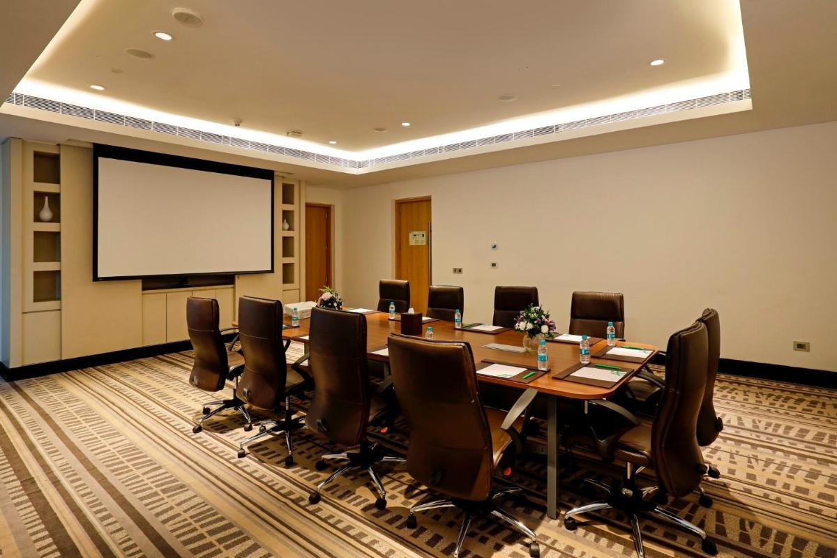 a conference room with a long table and chairs and a screen at Holiday Inn Chennai OMR IT Expressway by IHG in Chennai
