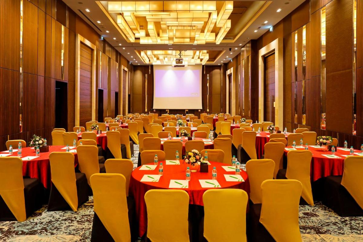 a conference room with tables and chairs and a screen at Holiday Inn Chennai OMR IT Expressway by IHG in Chennai