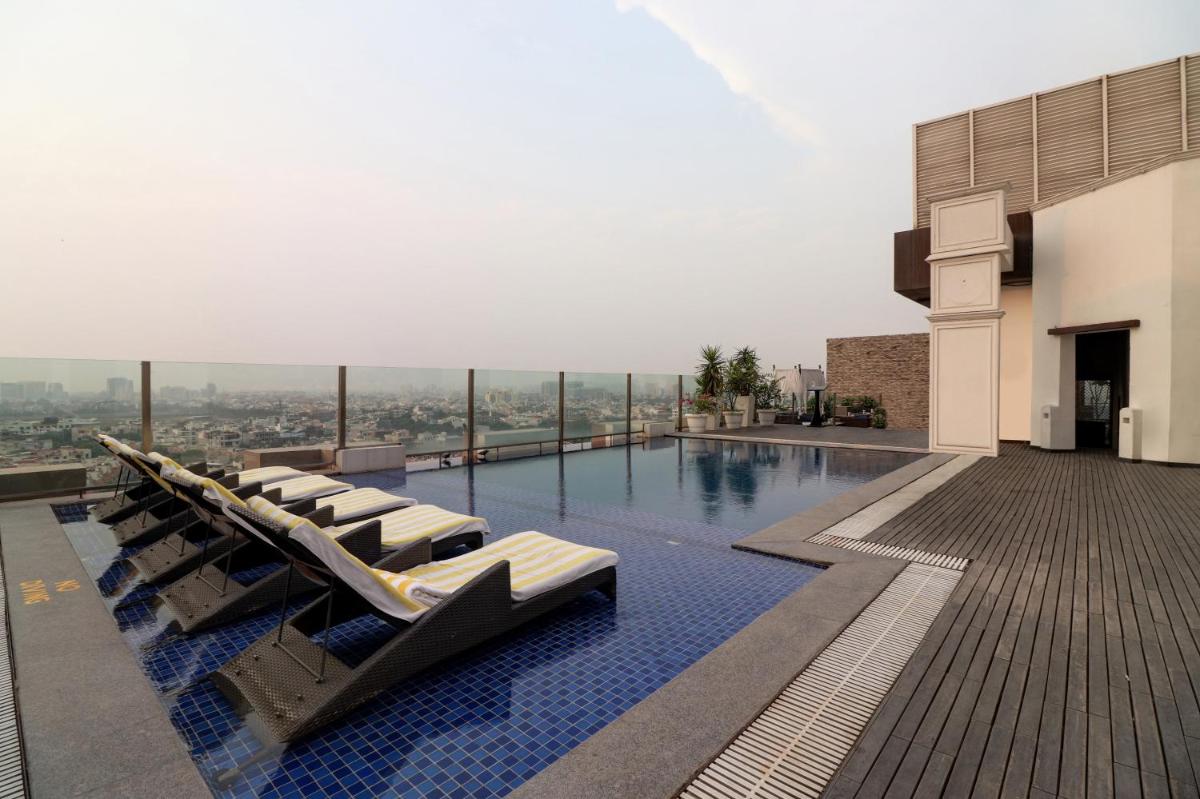 a swimming pool with lounge chairs on the roof of a building at DoubleTree by Hilton Gurugram Baani Square in Gurgaon
