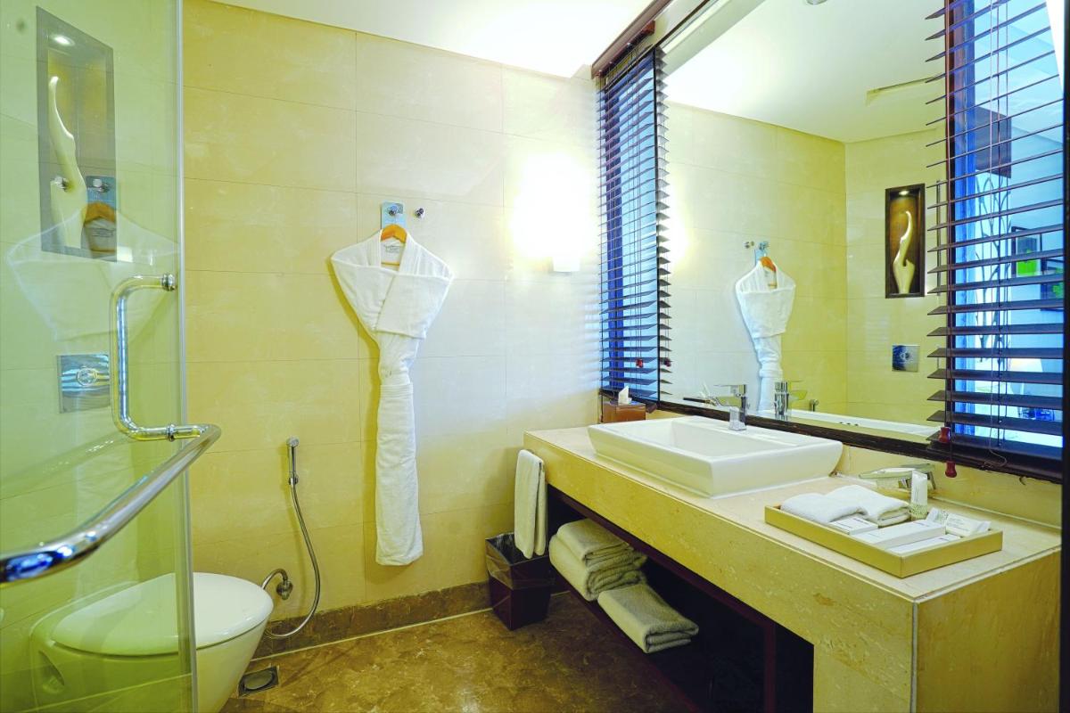a bathroom with a sink and a toilet and a mirror at DoubleTree by Hilton Gurugram Baani Square in Gurgaon a bathroom with a sink and a toilet and a mirror at DoubleTree by Hilton Gurugram Baani Square in Gurgaon