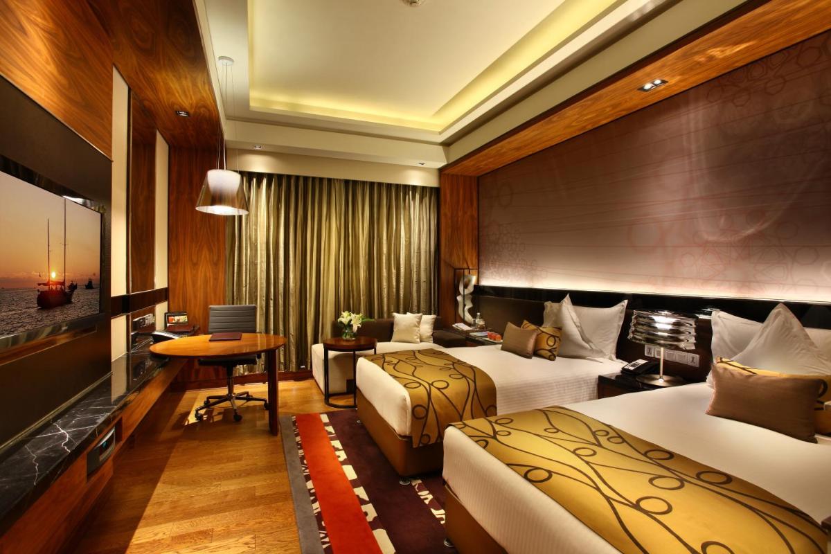 a hotel room with two beds and a desk at Crowne Plaza New Delhi Rohini by IHG in New Delhi a hotel room with two beds and a desk at Crowne Plaza New Delhi Rohini by IHG in New Delhi