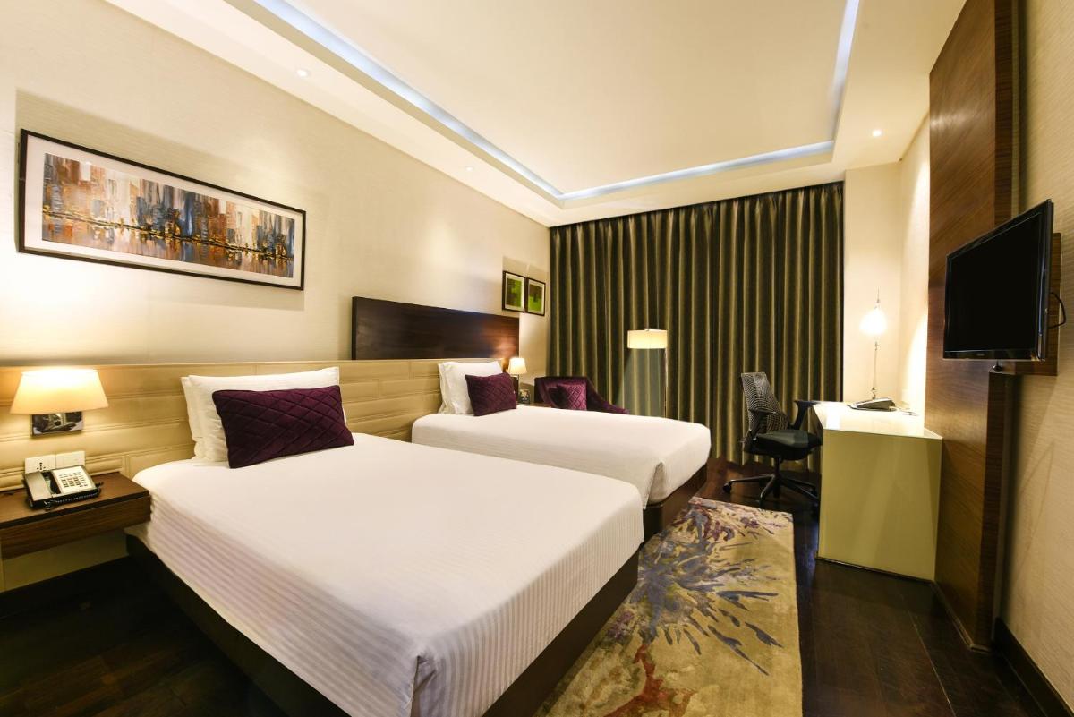 a hotel room with two beds and a television at DoubleTree by Hilton Gurugram Baani Square in Gurgaon