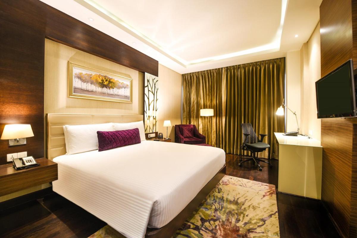 a hotel room with a white bed and a television at DoubleTree by Hilton Gurugram Baani Square in Gurgaon