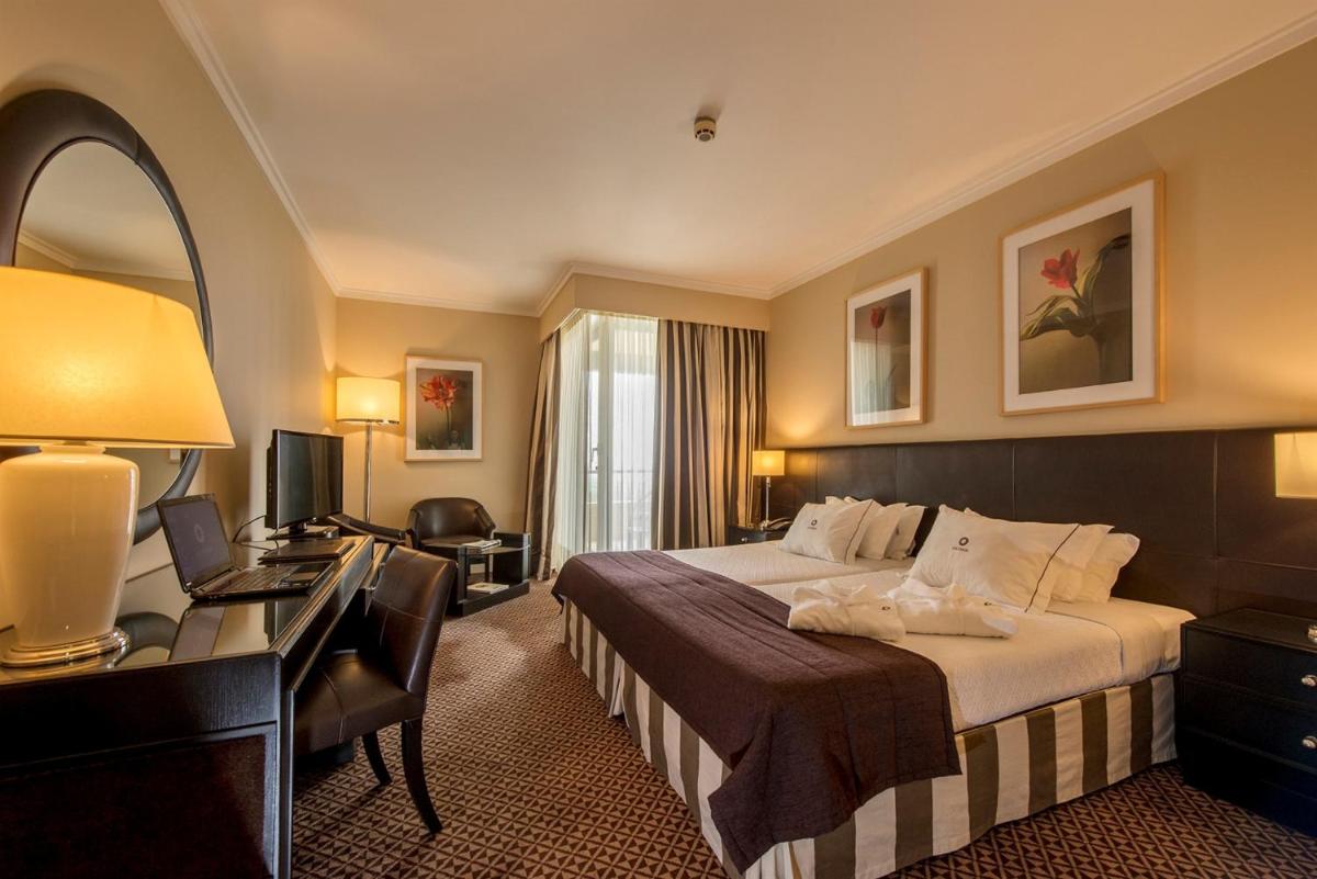 um quarto de hotel com uma cama e uma escrivaninha em Hotel Solverde Spa and Wellness Center em Vila Nova de Gaia um quarto de hotel com uma cama e uma escrivaninha em Hotel Solverde Spa and Wellness Center em Vila Nova de Gaia
