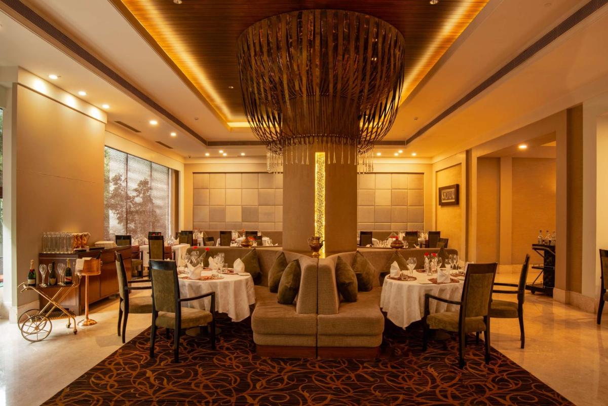 a restaurant with tables and chairs and a chandelier at Radisson Blu Bengaluru Outer Ring Road in Bengaluru