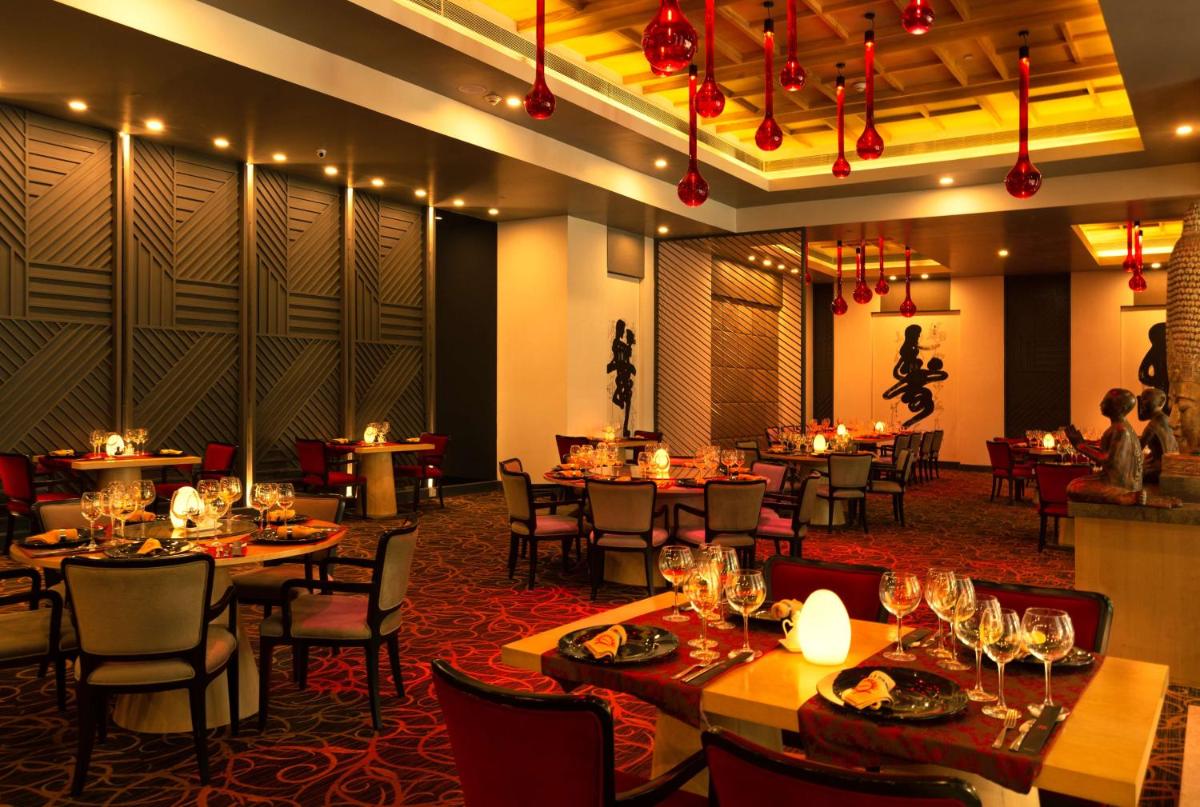 a dining room with tables and chairs and lights at Radisson Blu Bengaluru Outer Ring Road in Bengaluru