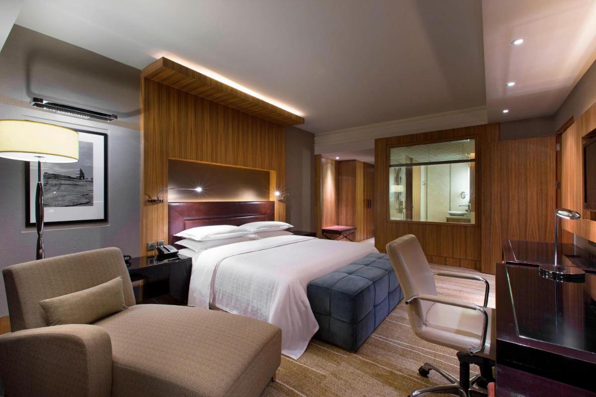 a hotel room with a large bed and chairs at Sheraton Grand Bangalore Hotel at Brigade Gateway in Bengaluru