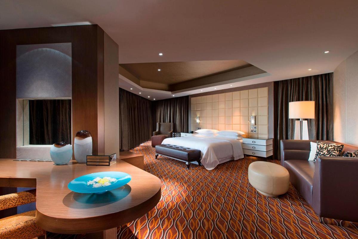 a large hotel room with a bed and a couch at Sheraton Grand Bangalore Hotel at Brigade Gateway in Bengaluru a large hotel room with a bed and a couch at Sheraton Grand Bangalore Hotel at Brigade Gateway in Bengaluru