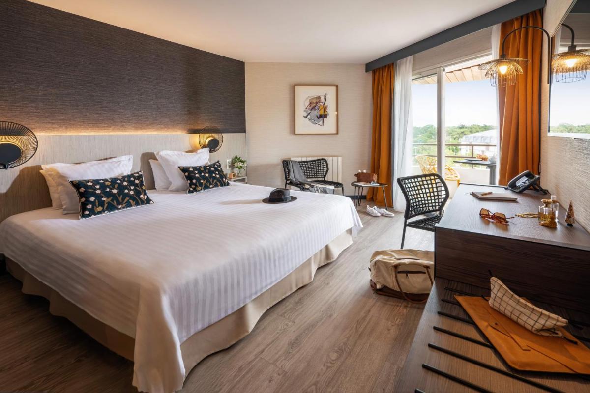 une chambre d'hôtel avec un grand lit et une fenêtre dans l'établissement Hôtel Valdys Thalasso & Spa - les Pins, à Saint-Jean-de-Monts