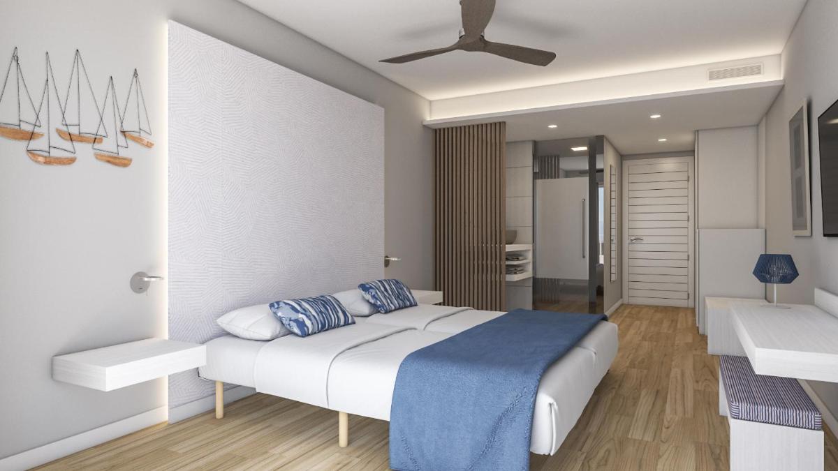 Un dormitorio con una cama y un ventilador de techo. en Blau Punta Reina, en Cala Mendia 100 fotos más