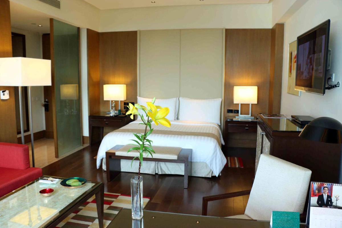 a hotel room with a bedroom with a bed and a table at The Oberoi Gurgaon in Gurgaon