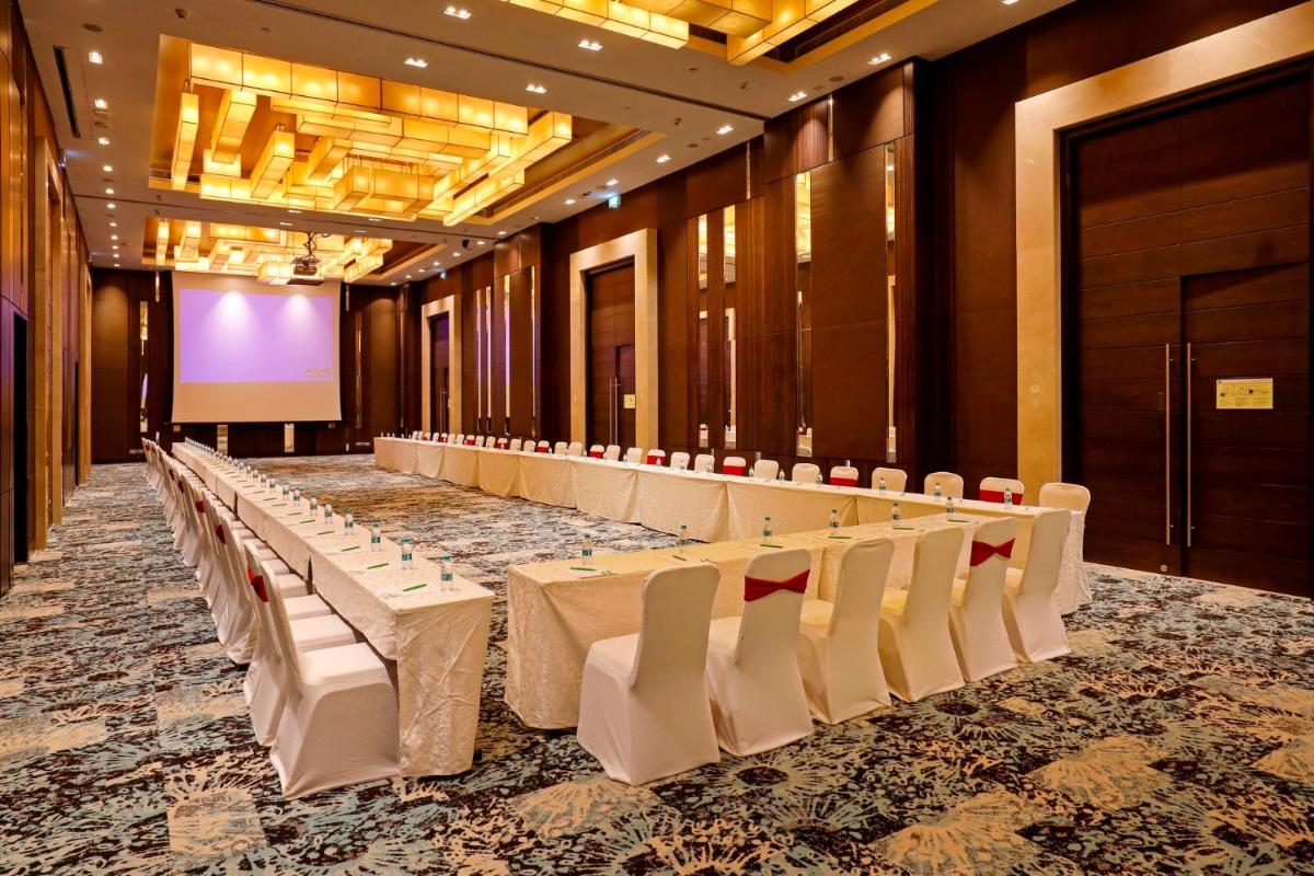 a conference room with tables and chairs and a screen at Holiday Inn Chennai OMR IT Expressway by IHG in Chennai