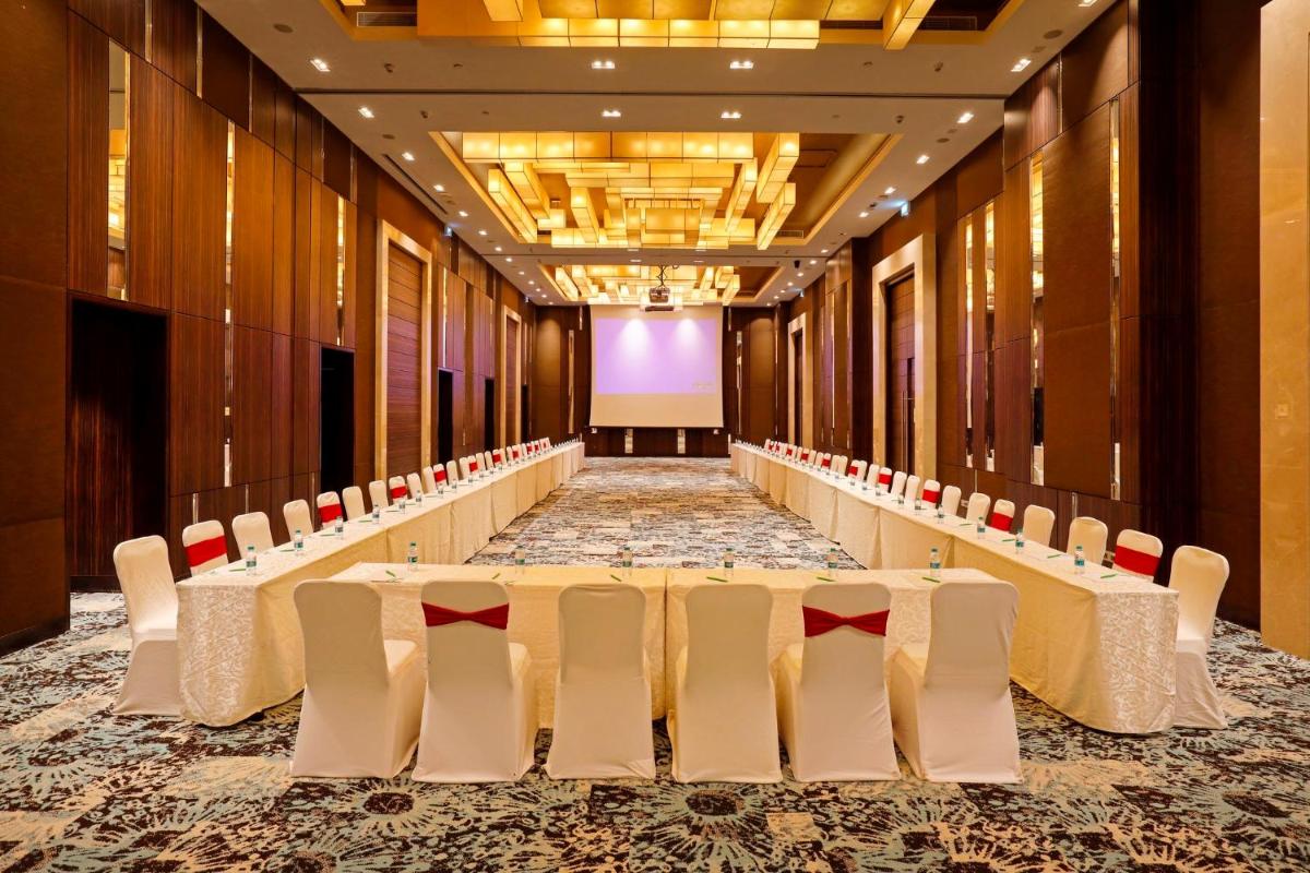 a banquet hall with white tables and chairs and a screen at Holiday Inn Chennai OMR IT Expressway by IHG in Chennai