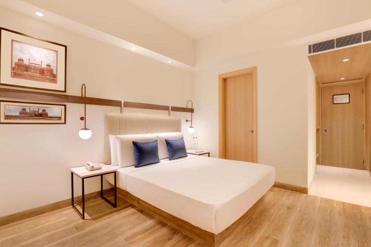 a bedroom with a large white bed with blue pillows at Lemon Tree Premier, Delhi Airport in New Delhi a bedroom with a large white bed with blue pillows at Lemon Tree Premier, Delhi Airport in New Delhi