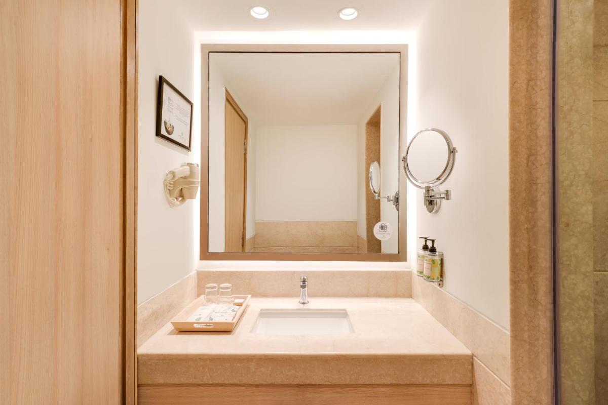 a bathroom with a sink and a large mirror at Lemon Tree Premier, Delhi Airport in New Delhi a bathroom with a sink and a large mirror at Lemon Tree Premier, Delhi Airport in New Delhi