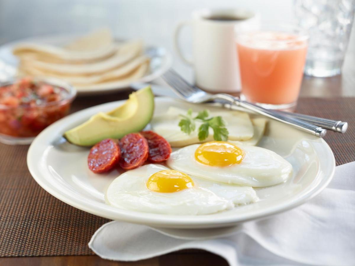 a plate of eggs and fruit on a table at Hilton Garden Inn, Trivandrum in Trivandrum