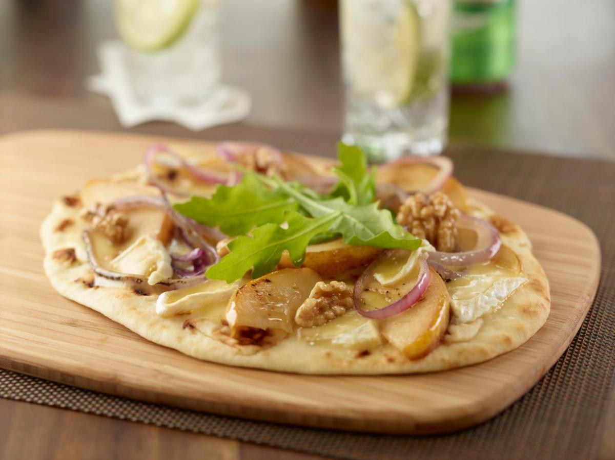 a pizza sitting on top of a wooden cutting board at Hilton Garden Inn, Trivandrum in Trivandrum
