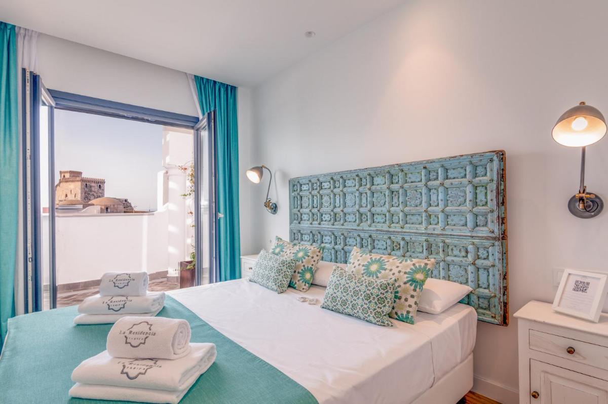 1 dormitorio con 1 cama grande con almohadas azules y verdes en La Residencia Puerto Hotel & Spa, en Tarifa