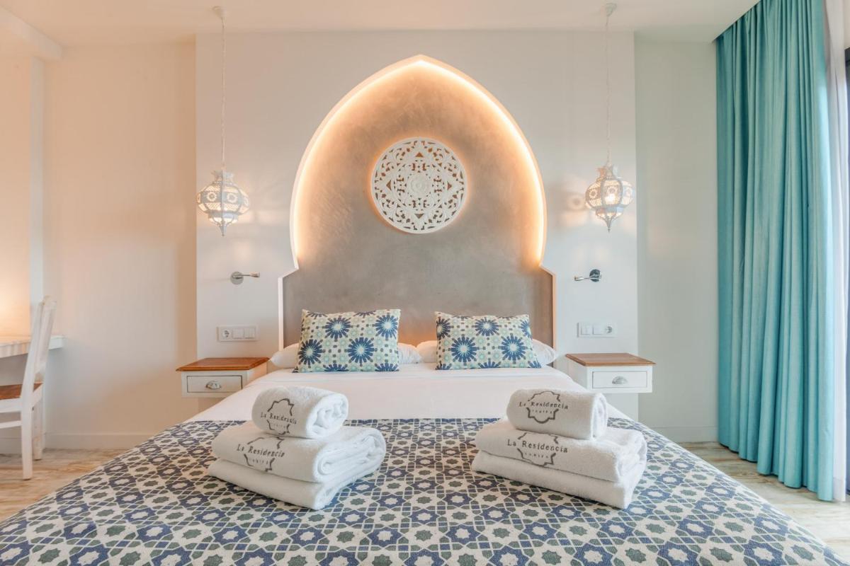 Un dormitorio con una cama grande con dos sillas. en La Residencia Puerto Hotel & Spa, en Tarifa