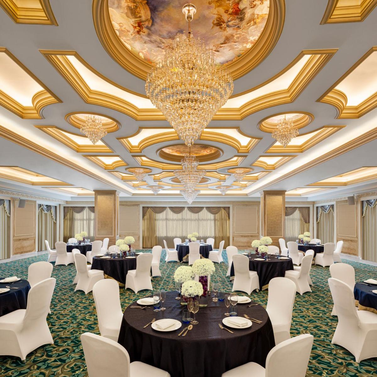 a banquet hall with tables and chairs and a chandelier at Vivanta Thiruvananthapuram in Trivandrum