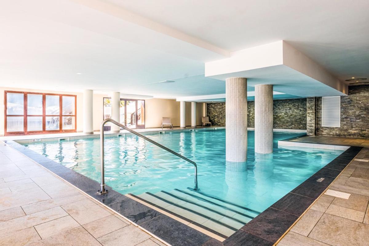 une grande piscine avec de l'eau bleue dans un immeuble dans l'établissement Résidence Pierre & Vacances Premium Les Terrasses d'Hélios, à Flaine