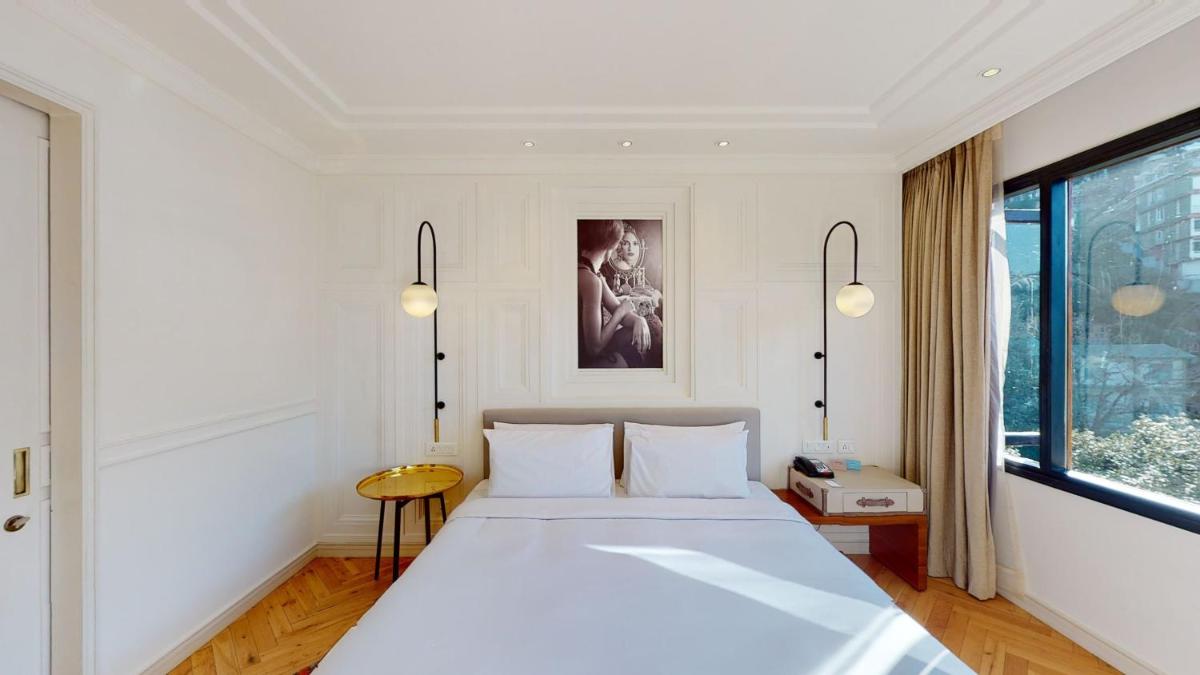 a bedroom with a large white bed and a window at Radisson Hotel Shimla in Shimla