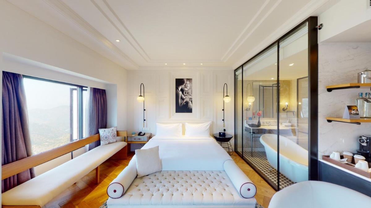 a bedroom with a large white bed and a tub at Radisson Hotel Shimla in Shimla