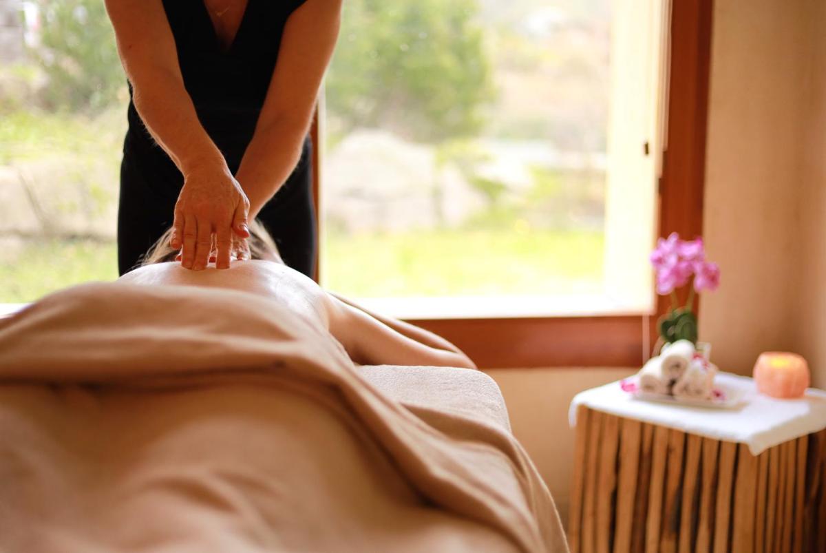 une femme en robe noire sèche les jambes d'une personne dans l'établissement LE CLOS DES SOURCES Hôtel & Spa, à Thannenkirch