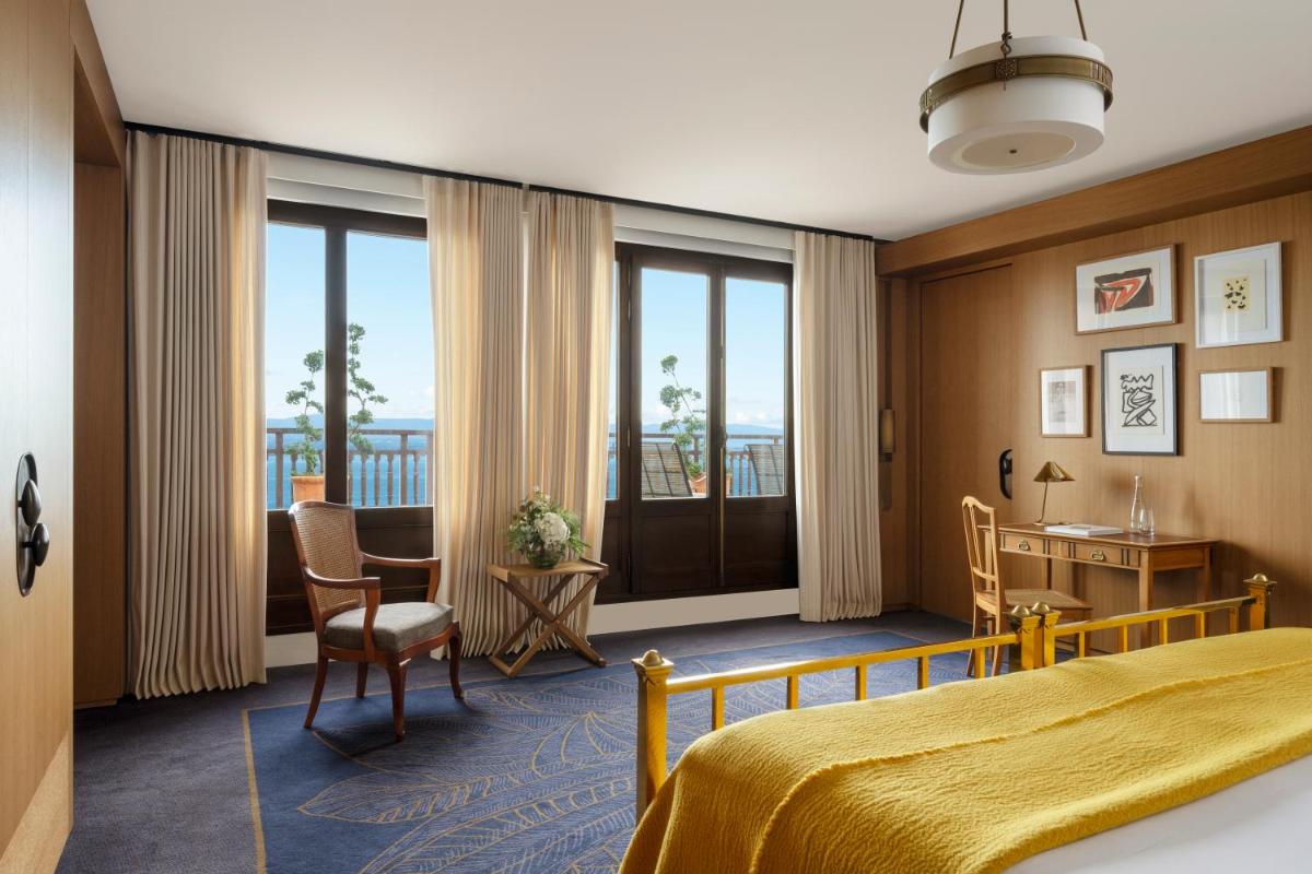 une chambre d'hôtel avec un lit, un bureau et des chaises dans l'établissement Hôtel Royal, à Évian-les-Bains