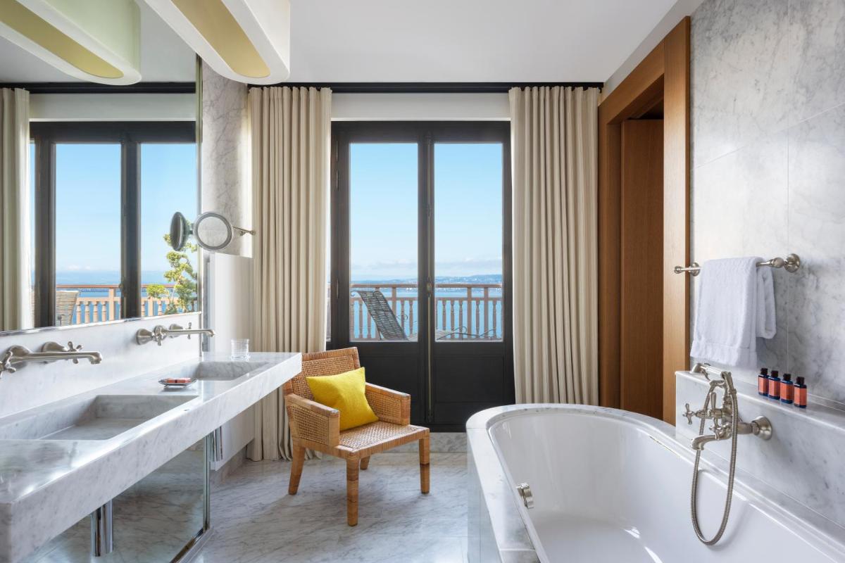 La salle de bains est pourvue de 2 lavabos et d'une baignoire avec une fenêtre. dans l'établissement Hôtel Royal, à Évian-les-Bains